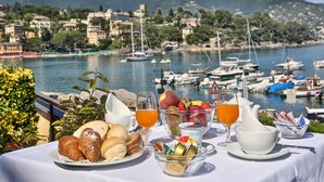 A table set with croissants, fruit, yogurt, and juice, overlooking a marina with boats and a mountainous backdrop. - Hotel Laurin (Santa Margherita Ligure)