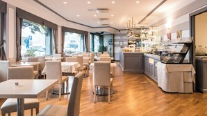 A modern restaurant with a long counter, multiple tables, and chairs. - Hotel Laurin (Santa Margherita Ligure)