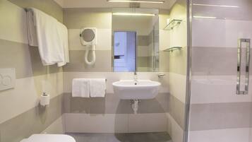 A modern bathroom with a toilet, sink, and glass shower enclosure.
