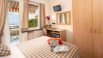 Una habitación de hotel con cama, escritorio, televisor y armario.