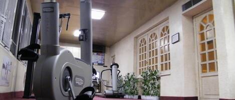 A gym with stationary bikes, a treadmill, and a wall-mounted exercise machine.