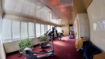 A gym with exercise equipment, windows, and a carpeted floor.