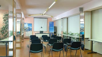 A conference room with a long table, chairs, and a projector screen.