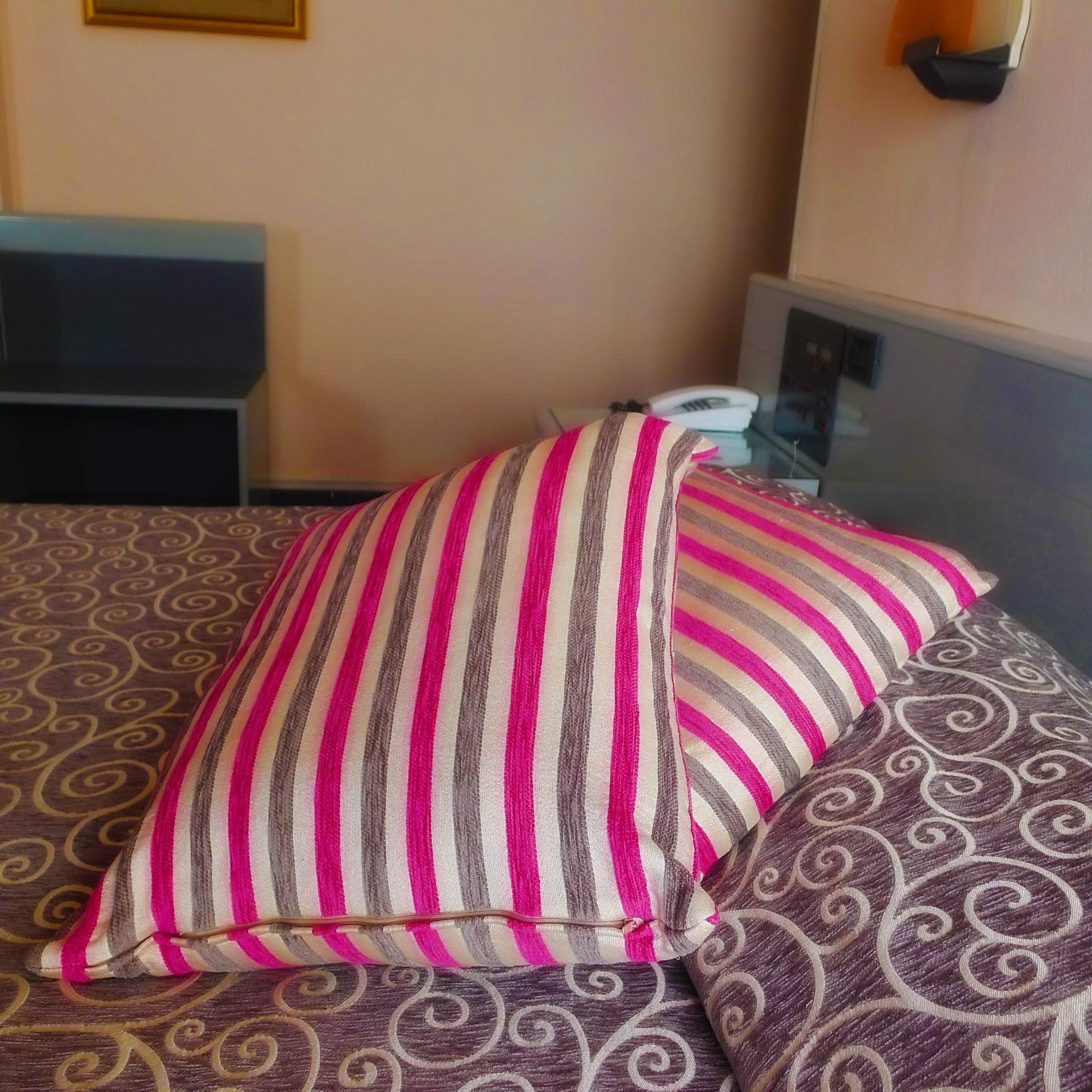 A bed with striped pillows and a patterned bedspread.