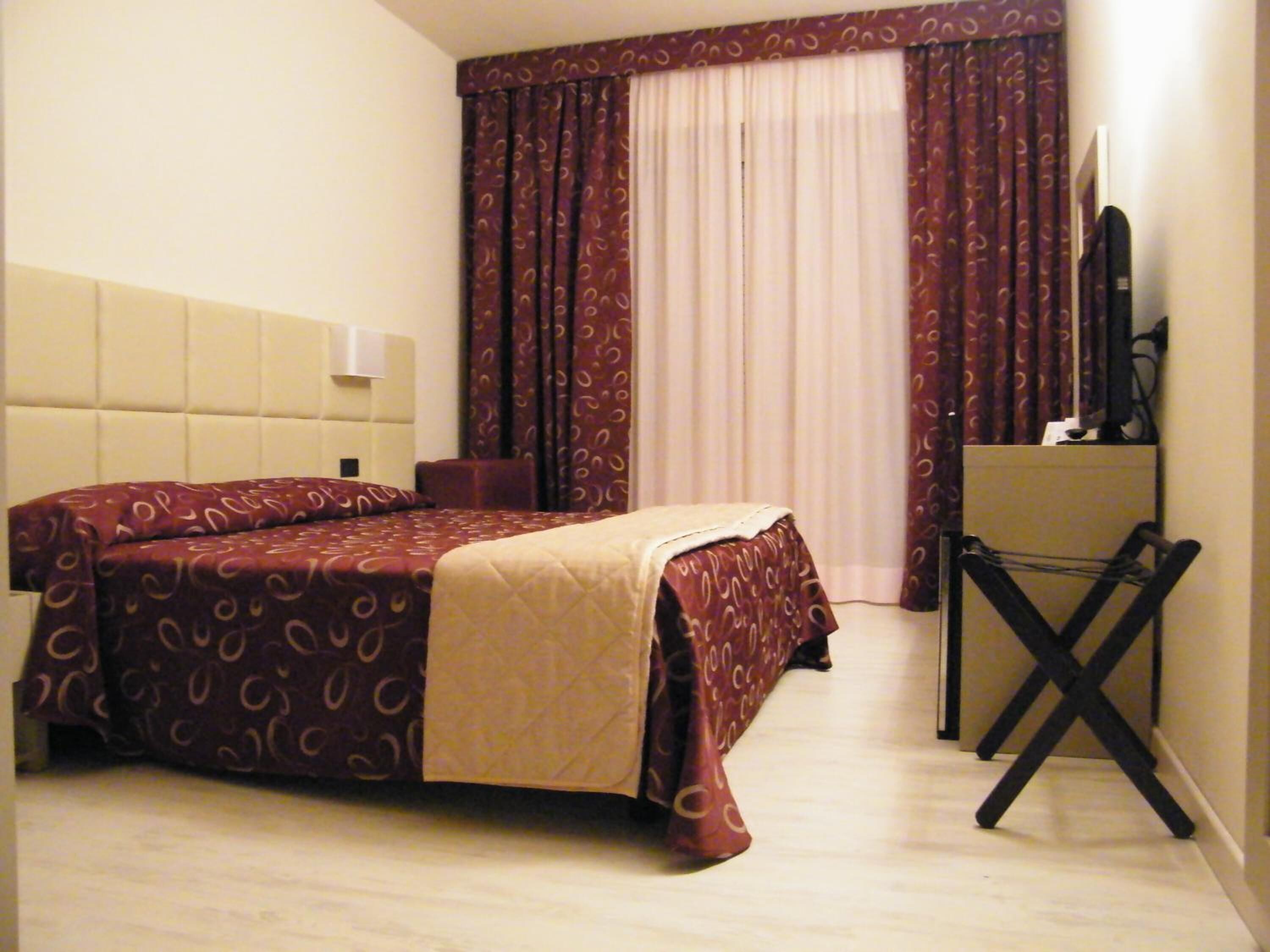 A hotel room with a bed, a desk, and a chair.
