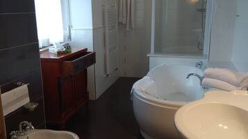 A bathroom with a toilet, bidet, bathtub, and two sinks.