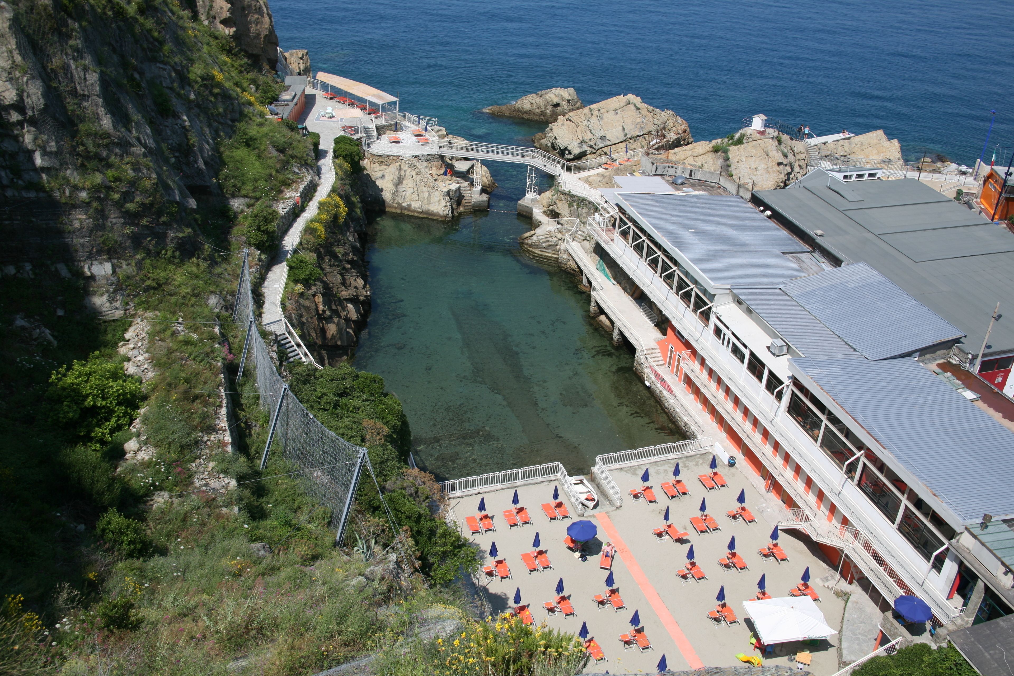 Un hotel sulla costa con un litorale roccioso, un molo e zone salotto all'aperto con ombrelloni.