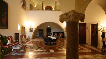 Un'imponente hall con pavimento in marmo, colonne classiche e soffitto alto con archi.