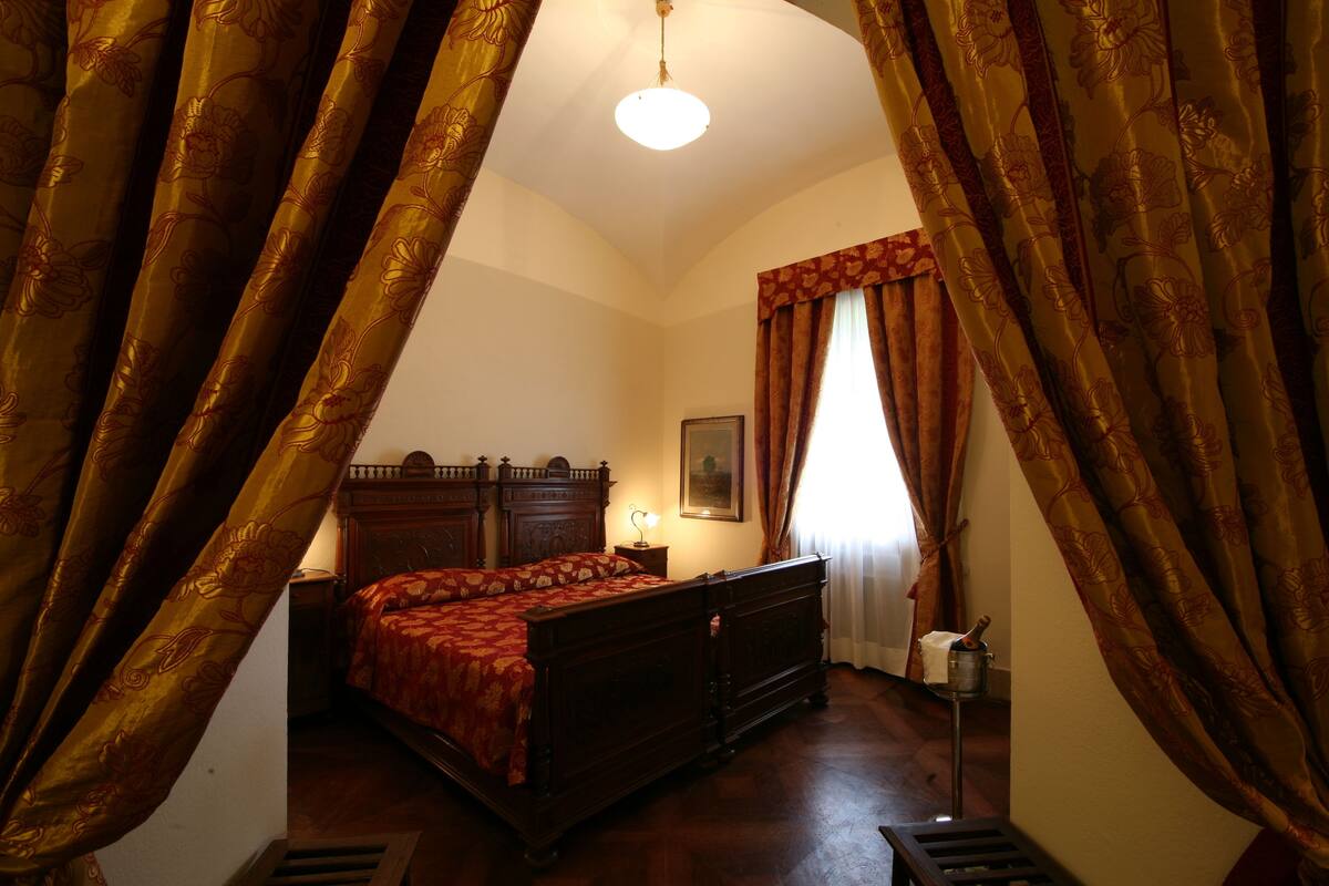 Ein Schlafzimmer mit einem hölzernen Bett, einem Nachttisch, einer Lampe und einem Gemälde an der Wand.