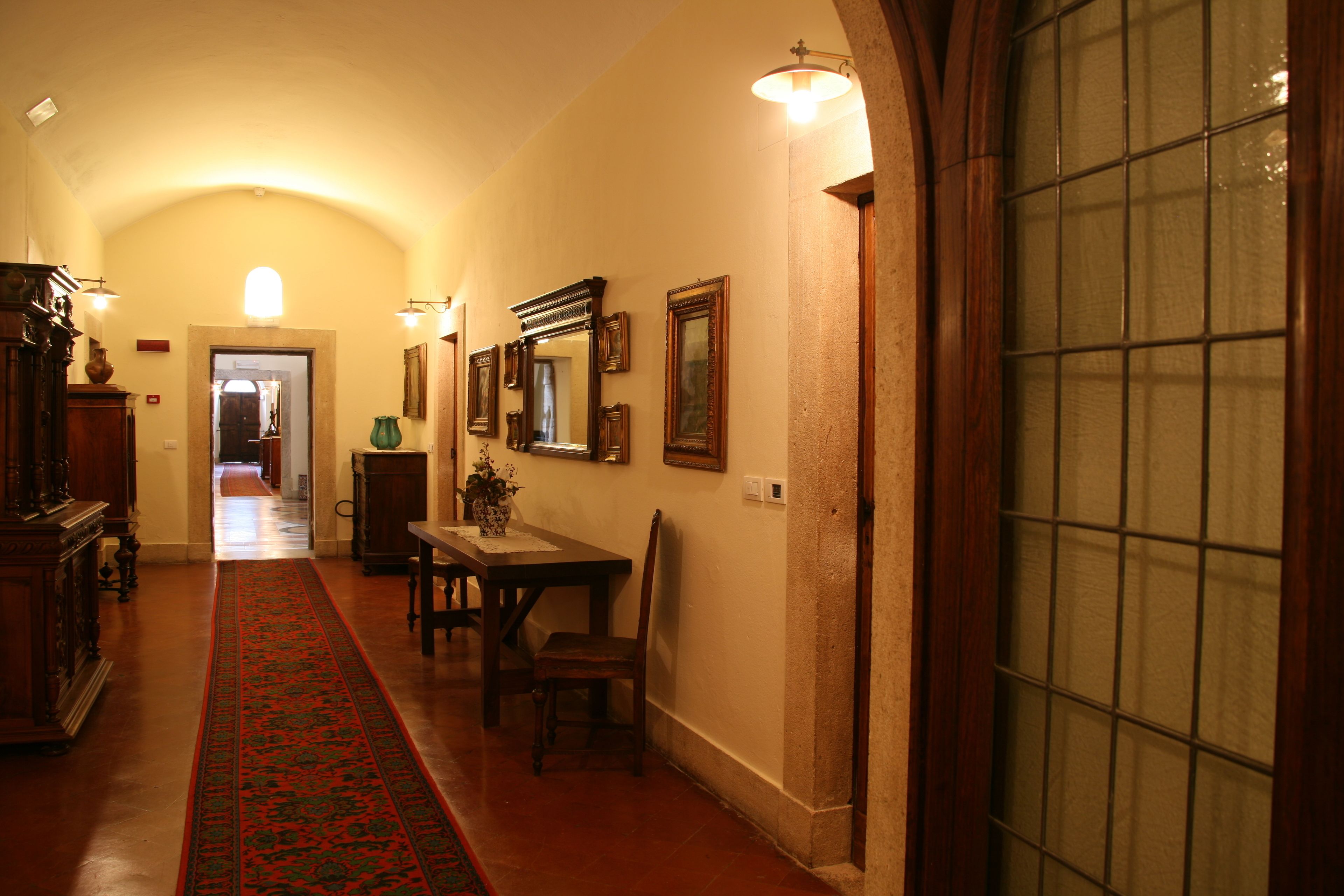 Un pasillo con alfombra roja, muebles de madera y cuadros en las paredes.