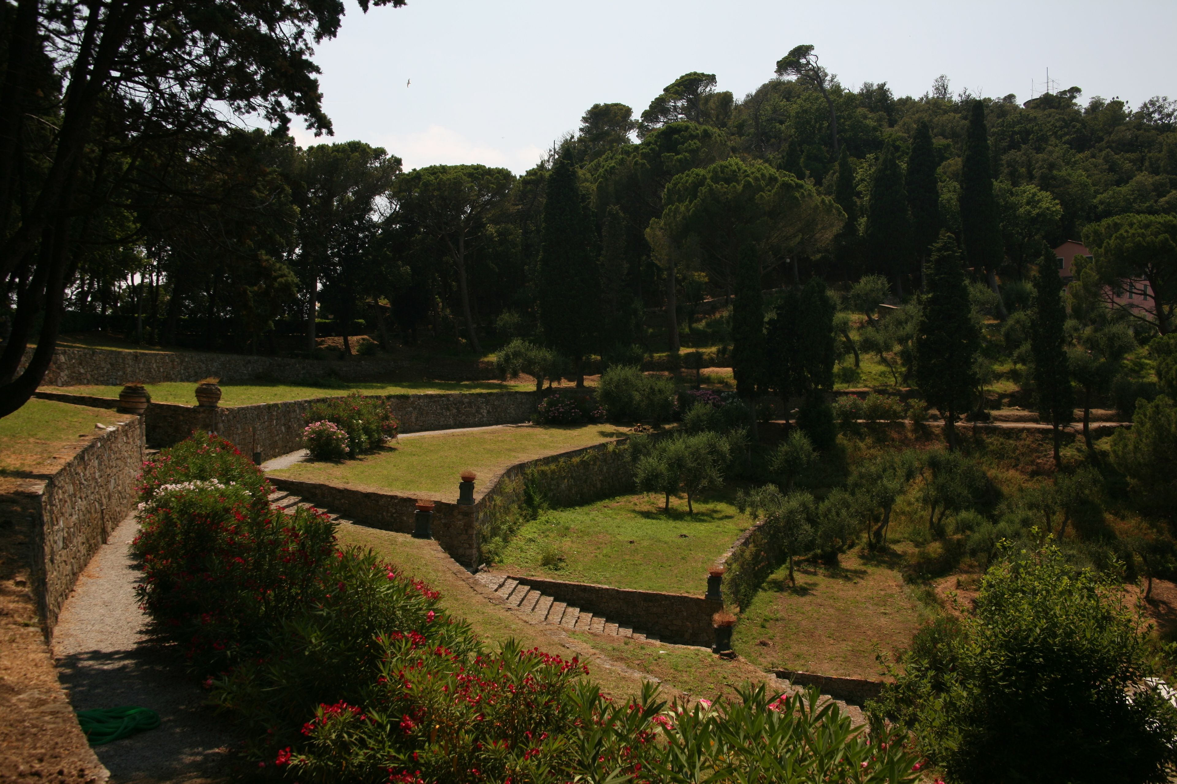 Un jardín ajardinado con muros de piedra, senderos y diversas plantas.