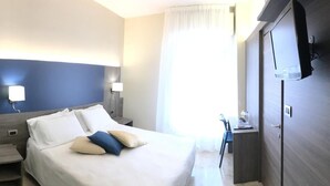 Een hotelkamer met twee bedden, een bureau en een televisie.