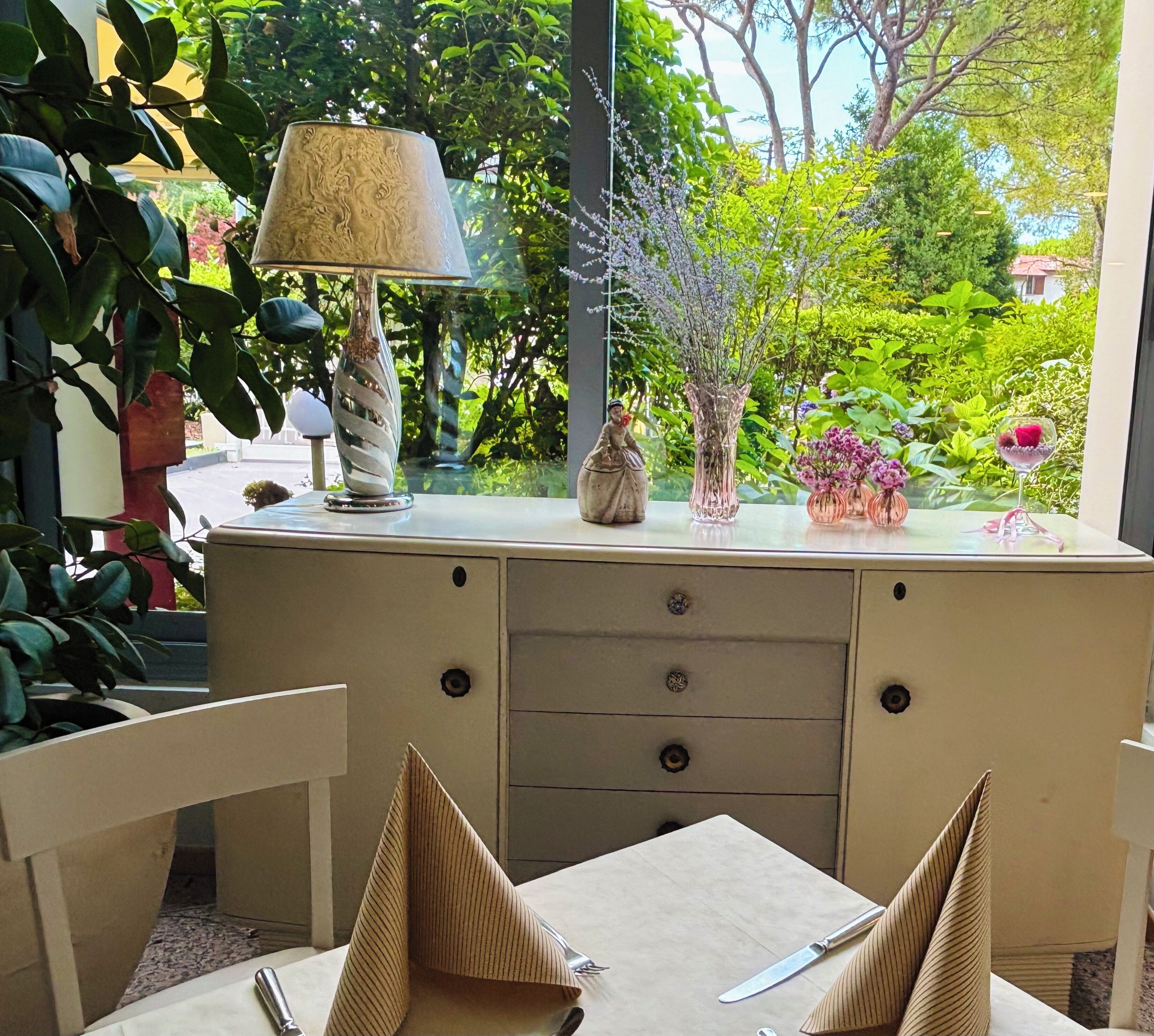 Un comedor con una mesa dispuesta para dos personas, una lámpara decorativa y un florero con flores.