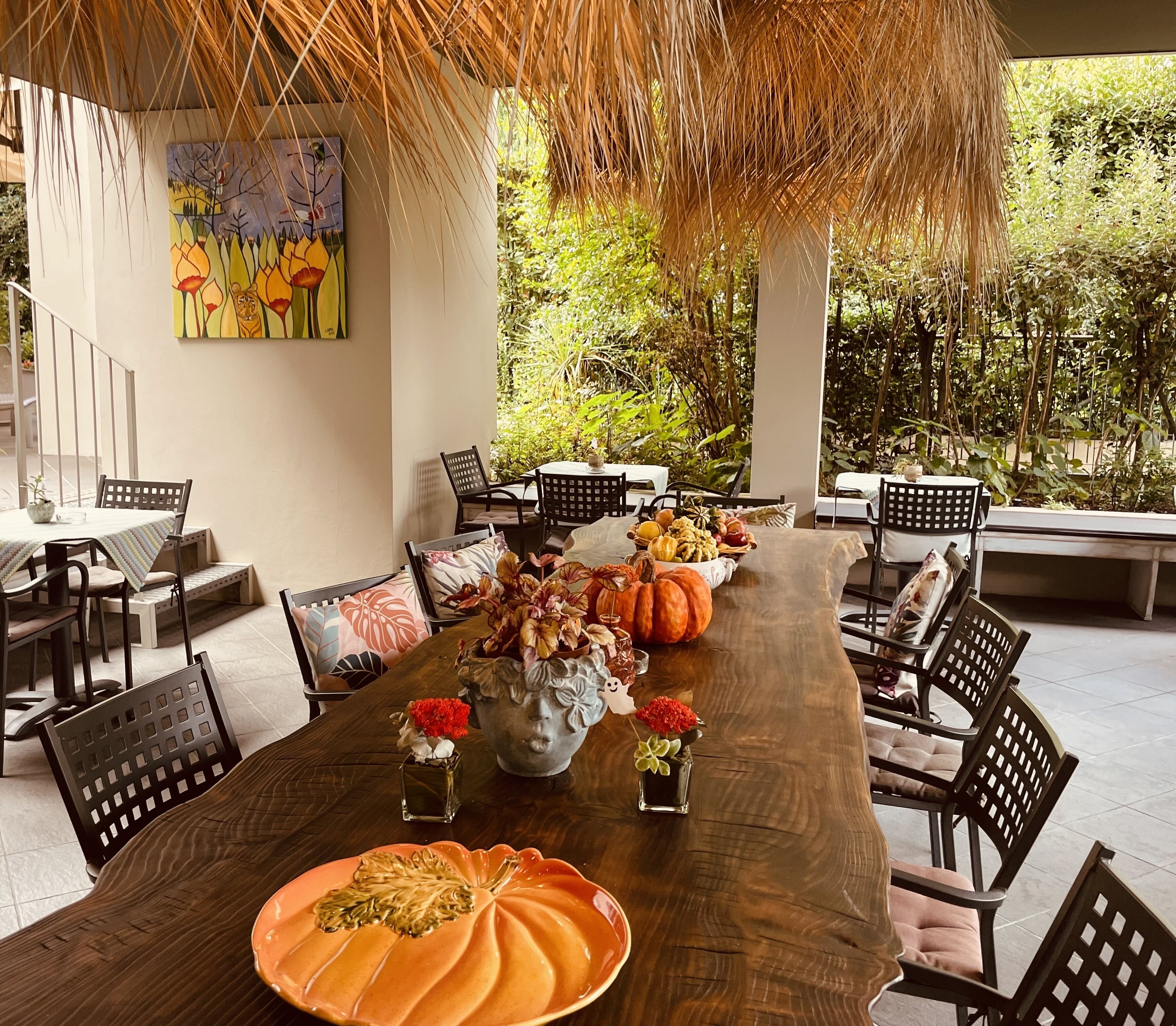 A dining area with a long wooden table, black chairs, and a variety of decorative items including pumpkins and flowers.