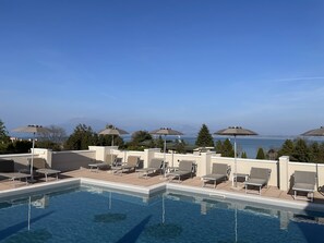 A pool area with lounge chairs and umbrellas, overlooking a body of water and distant mountains. - Hotel Alfieri (Sirmione)