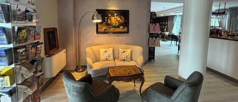Eine moderne Hotellobby mit einer Couch, zwei Sesseln, einer Stehlampe und einem Gemälde.