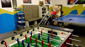 Relax in this vibrant room with a foosball table, ping pong table, and plush sofa, perfect for entertainment and leisure.