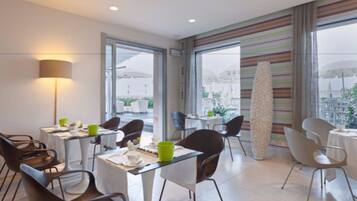 A modern dining area with tables and chairs, large windows, and a decorative column.
