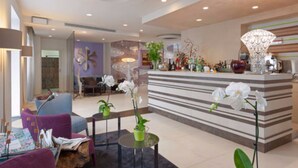 A modern lobby with a reception desk, seating area, and decorative elements. - Hotel Eden (Sirmione)