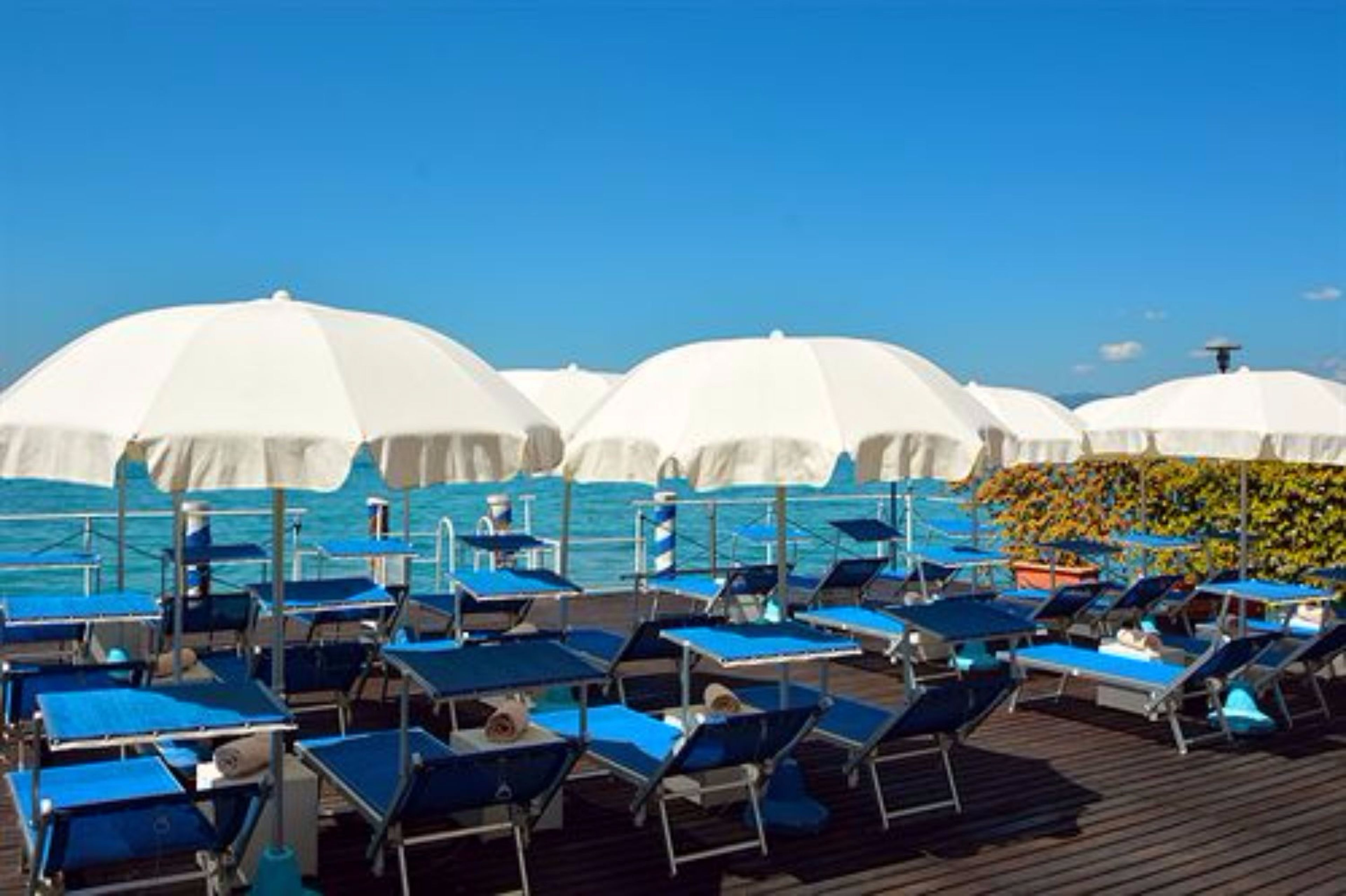 Une terrasse avec des chaises longues et des parasols, donnant sur la mer.