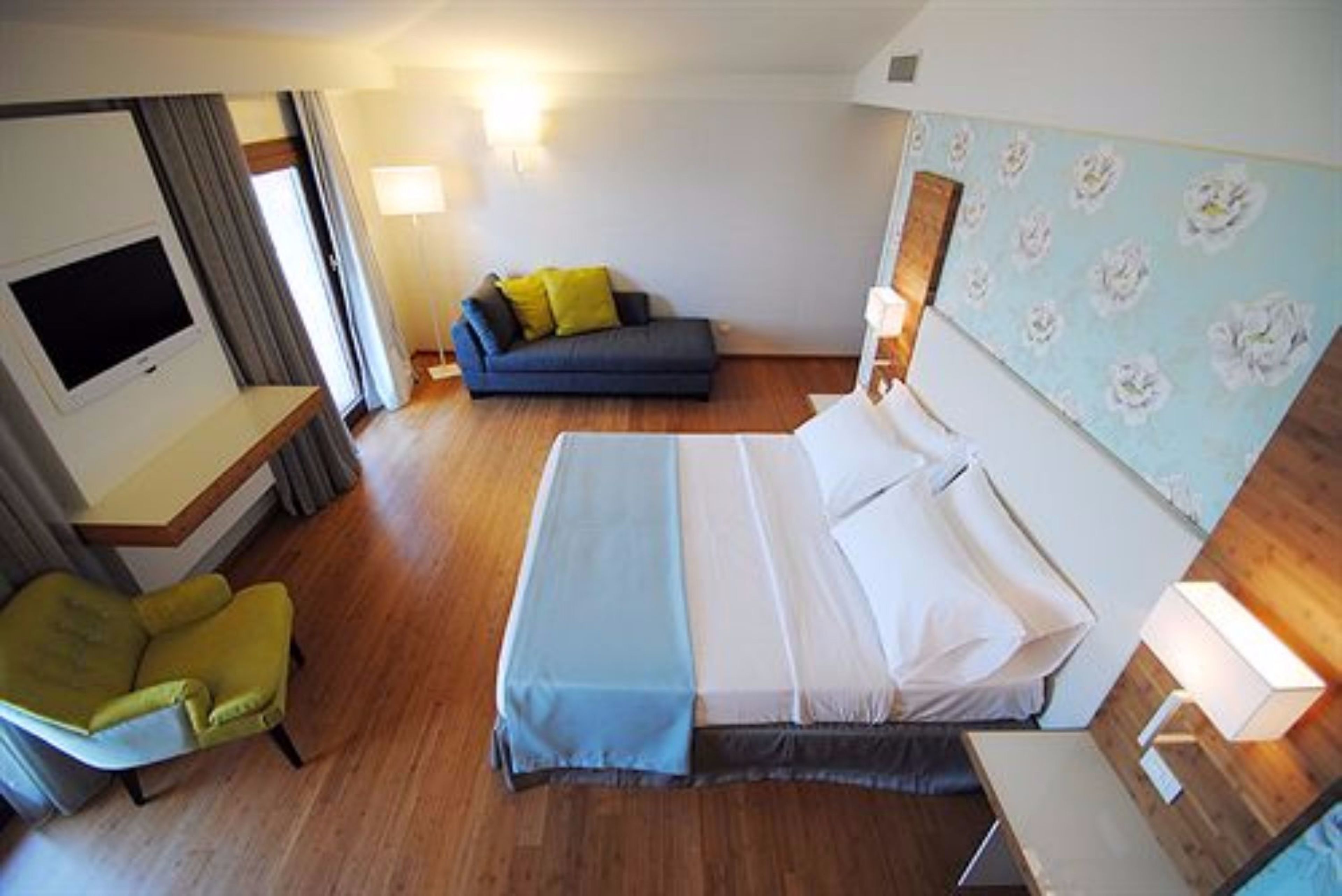 Una habitación de hotel con una cama, un sofá, una silla y un televisor.