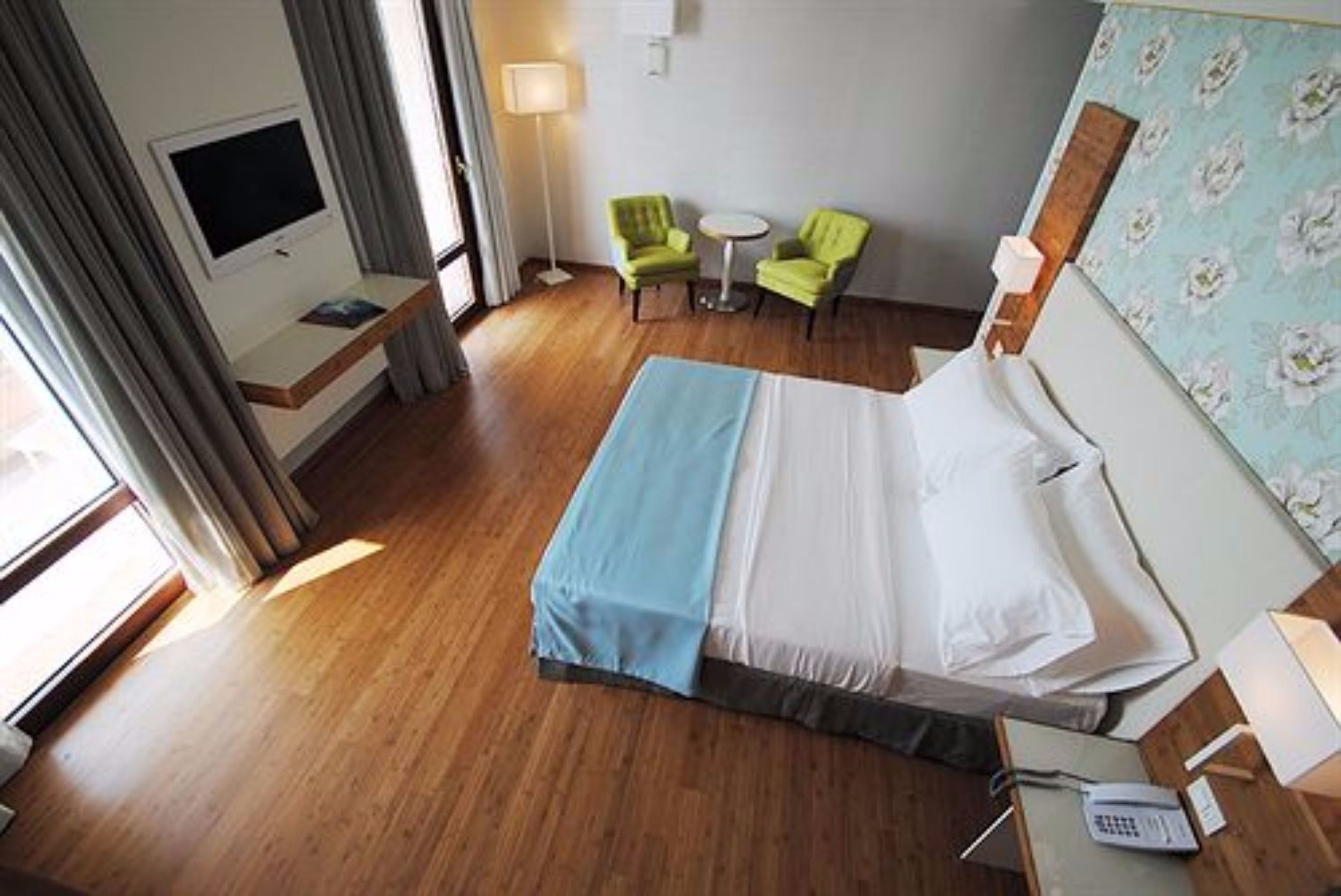 Habitación de hotel con cama, televisor, escritorio con teléfono, dos sillas y una mesita.