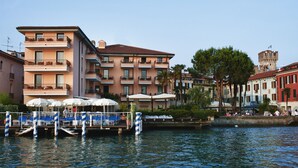 A waterfront hotel with balconies, outdoor seating, and a view of the water. - Hotel Eden (Sirmione)