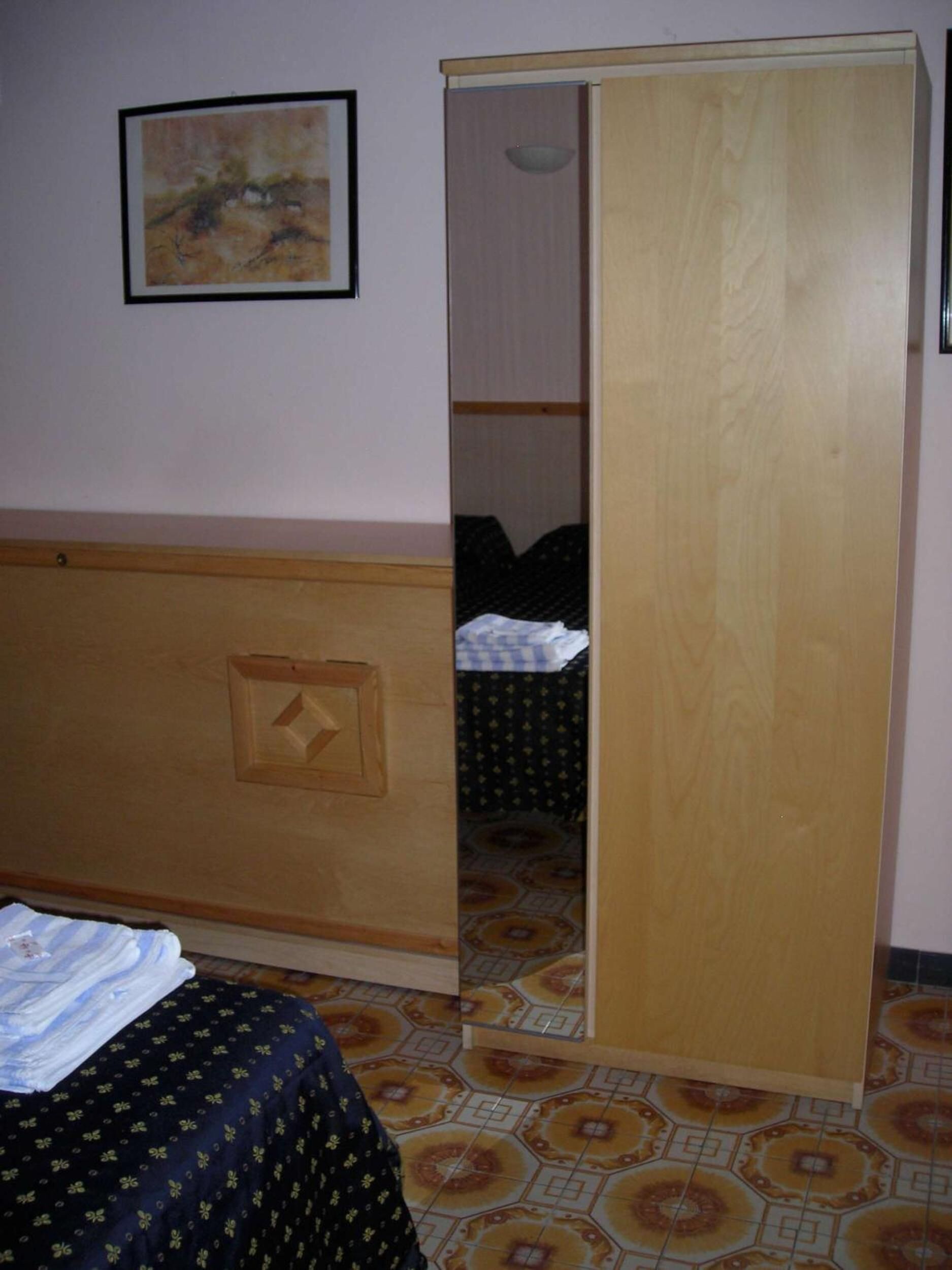 A room with a bed, a wardrobe, and a painting on the wall.
