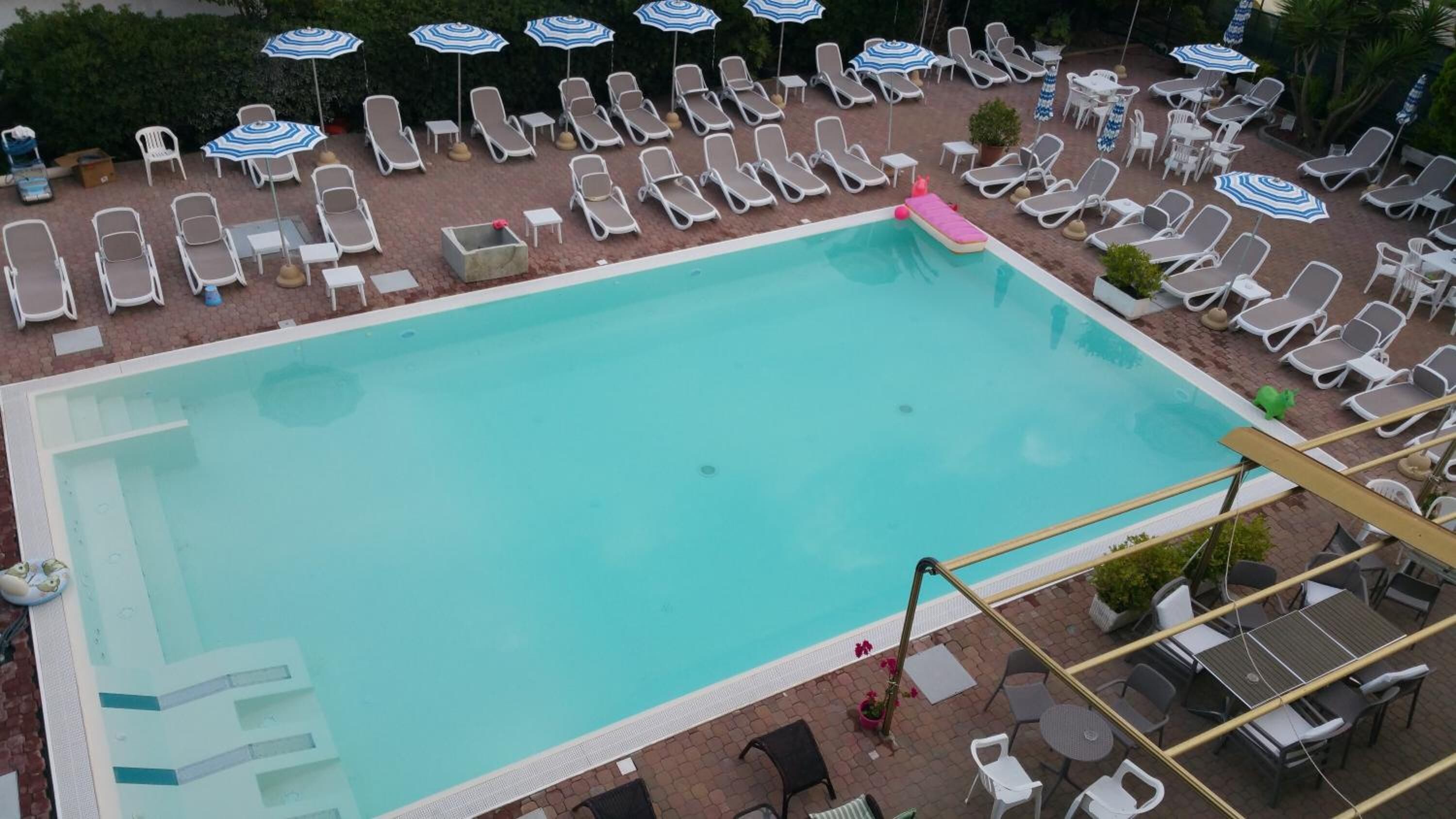 Una piscina rectangular envoltada de gandules i para-sols.