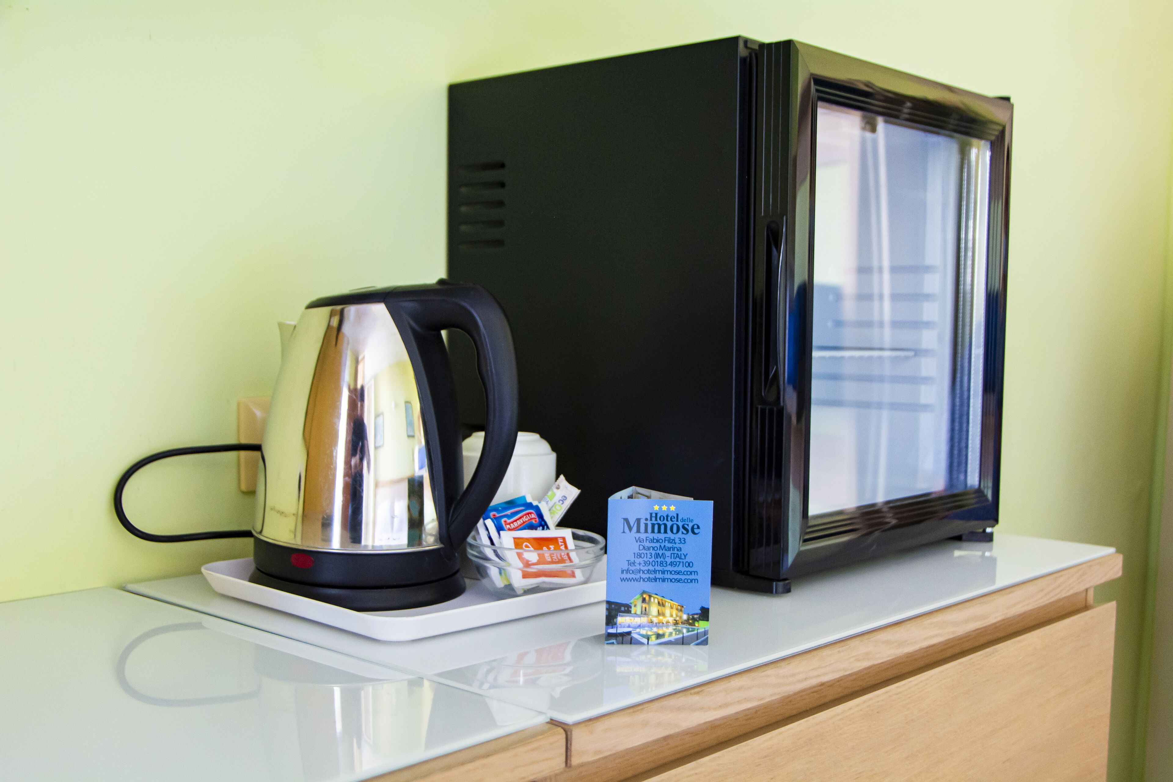 A kitchenette with a coffee maker, a microwave, and a small sign for Hotel Mimoise.