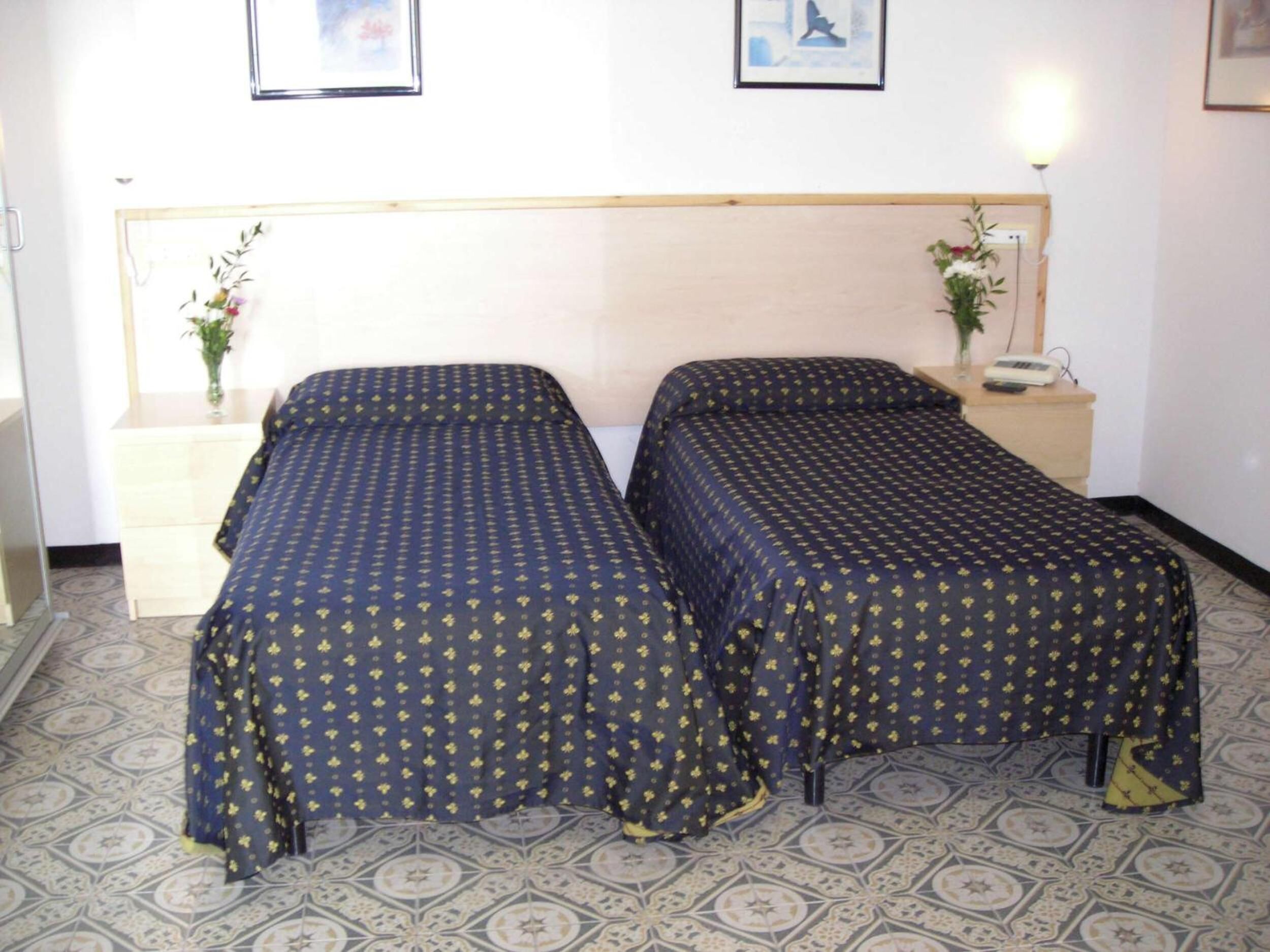 Un letto matrimoniale con testiera, due comodini e una lampada a parete.