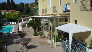 A hotel courtyard with a swimming pool, outdoor seating, and a covered area with bicycles.