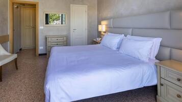 Une chambre à coucher avec un grand lit, une table de chevet avec une lampe, une chaise et une armoire.