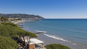 A coastal view with a beach, a pier, and a town in the background. - B&B Hotel Diano Marina Palace (Diano Marina)