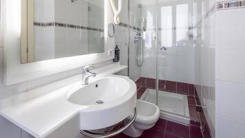 A modern bathroom with a white sink, a mirror, a shower, and a toilet.
