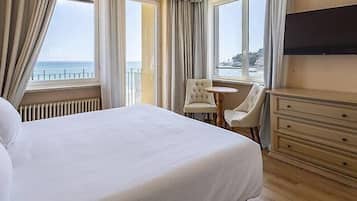Ein Hotelzimmer mit einem großen Bett, einem kleinen runden Tisch, einem Stuhl, einem Schminktisch und einem Fernseher.