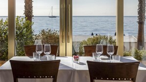 A table set for two with a view of the sea through large windows. - B&B Hotel Diano Marina Palace (Diano Marina)