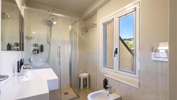 Un baño moderno con ducha acristalada, lavamanos grande y bidé.