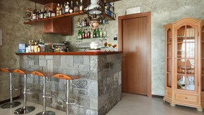 A bar area with a stone counter, three stools, and a wooden cabinet with glassware. - Piccolo Hotel (Diano Marina)