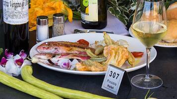 A dining table with a plate of food, a wine bottle, a wine glass, and a hotel room number sign.