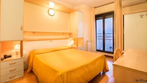 Une chambre d’hôtel avec un lit, des tables de chevet, un bureau et une vue sur l’extérieur.