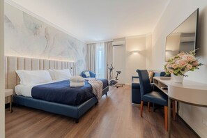 Habitación de hotel moderna con una cama grande, un escritorio, una silla, un espejo y una pared decorada con un cuadro abstracto de gran tamaño.