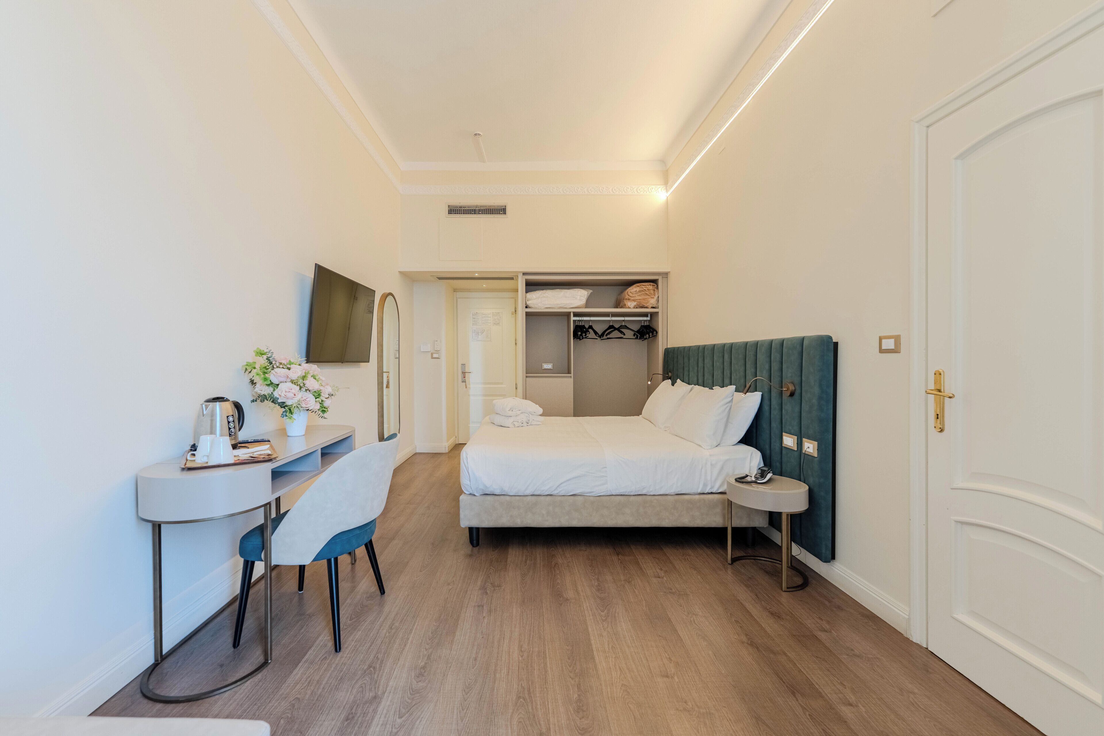 Una habitación de hotel con cama, mesita de noche, silla, escritorio y armario.