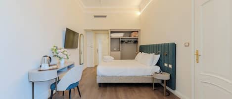 A hotel room with a bed, bedside table, chair, desk, and a wardrobe.