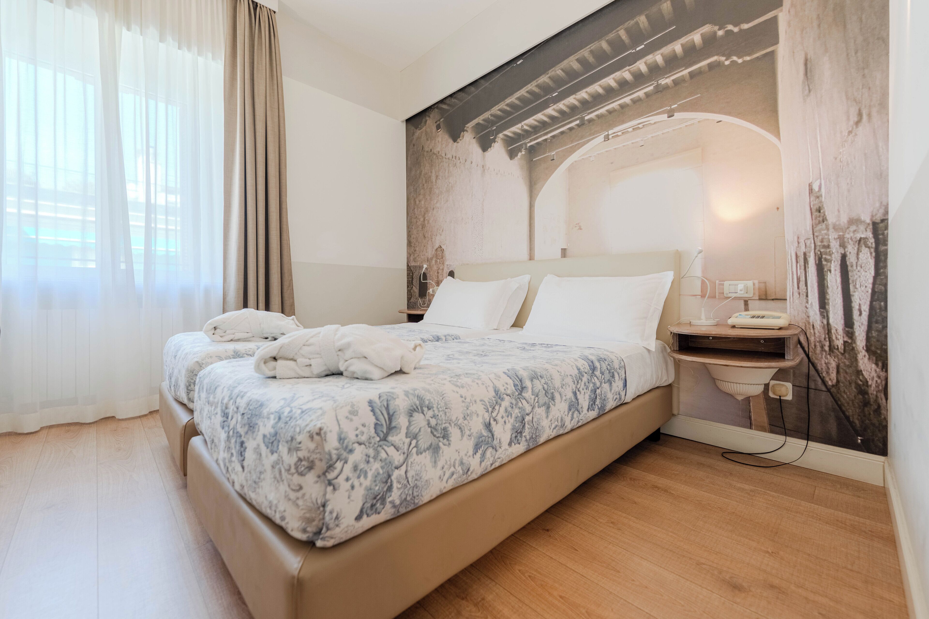 Un dormitorio con una cama, una mesita de noche, una lámpara y un teléfono instalado en la pared.