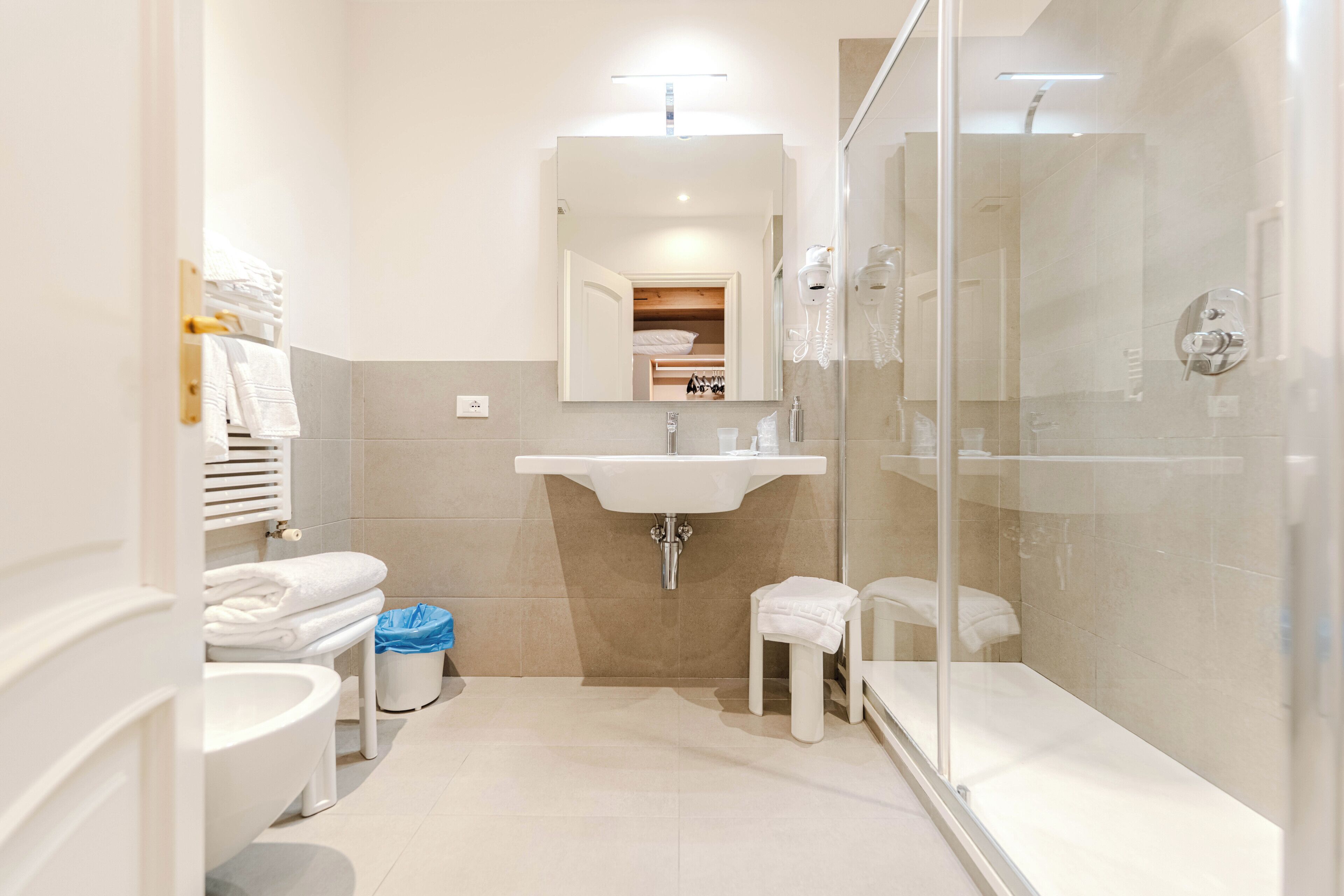 A bathroom with a toilet, sink, glass shower enclosure, and a mirror.