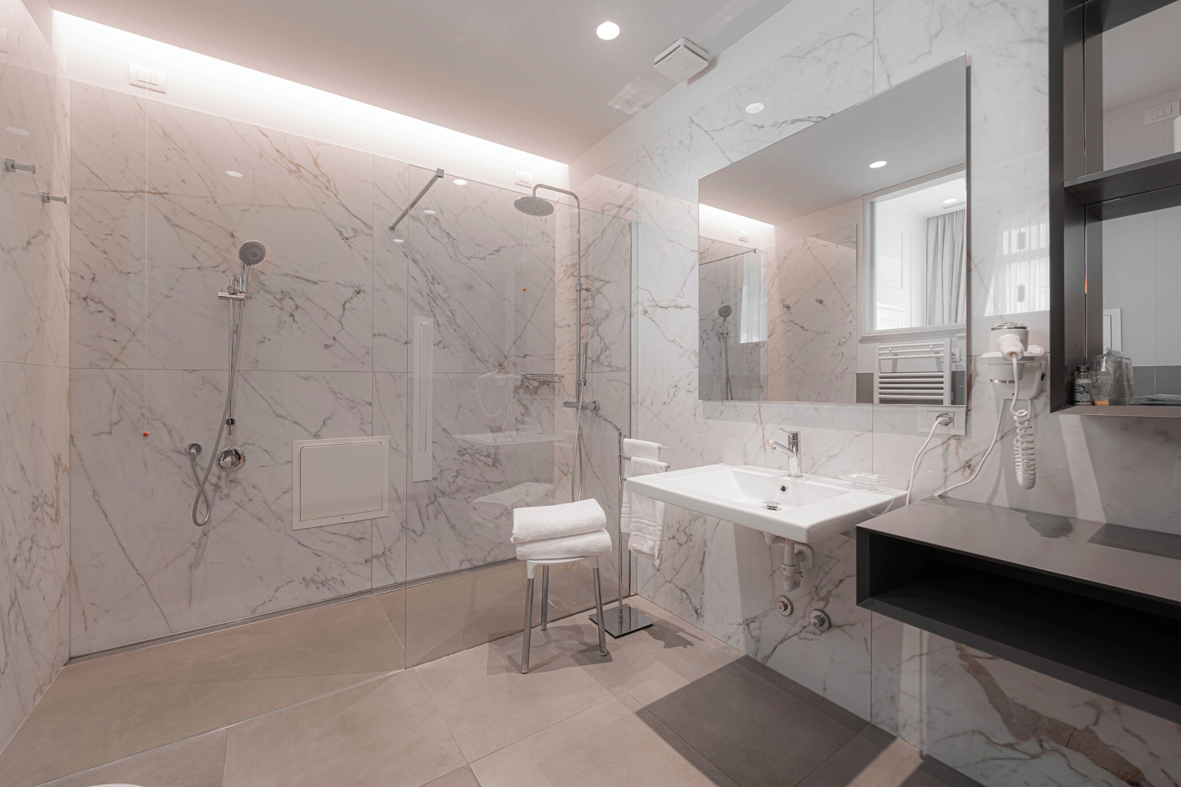 A modern bathroom with a glass-enclosed shower, a white sink, and a large mirror.