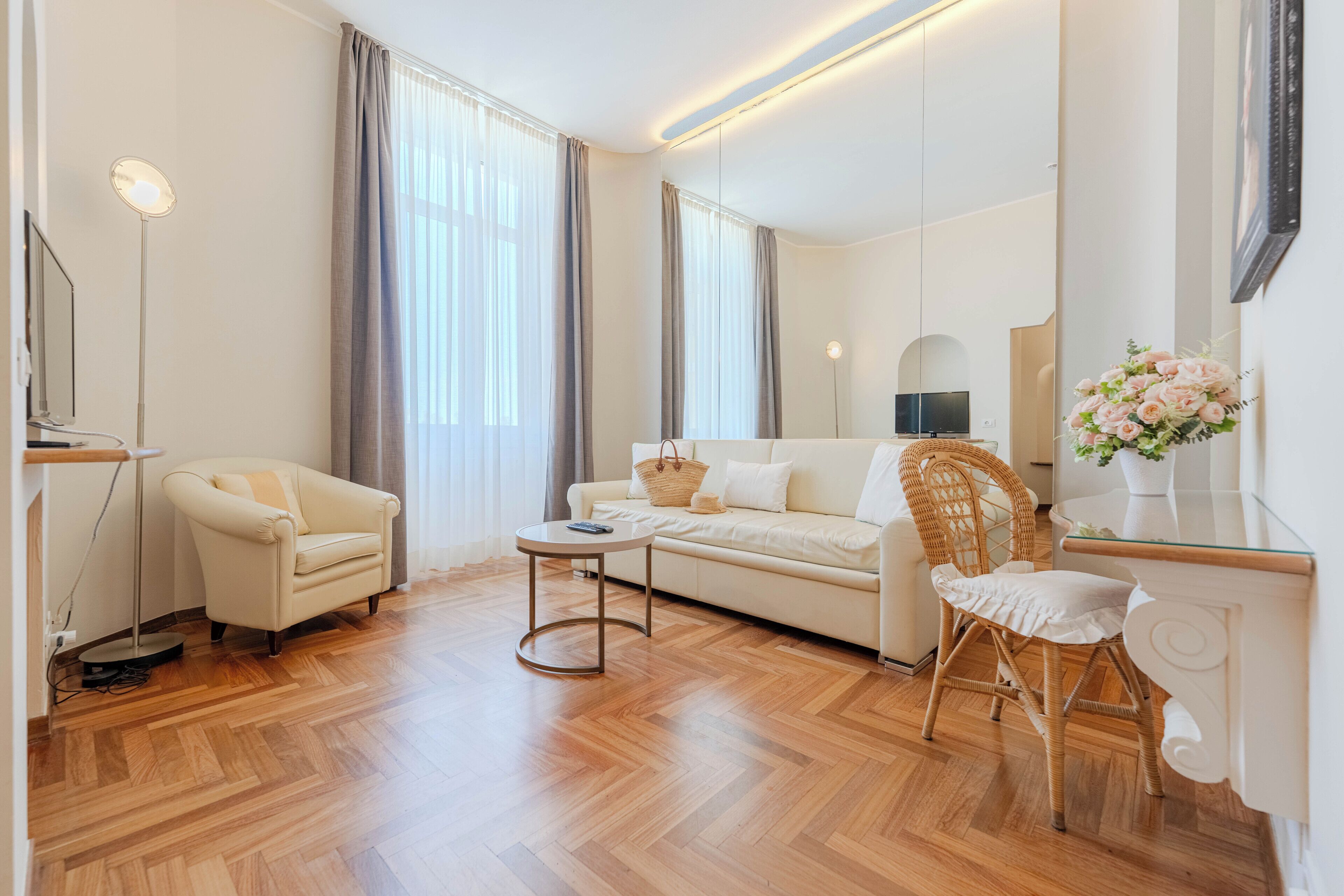 Ein modernes Wohnzimmer mit einer Couch, einem Sessel, einem runden Tisch und einem Korbstuhl.