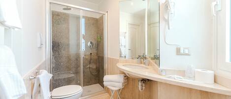 Un baño moderno con ducha de vidrio, lavamanos, inodoro y espejo.