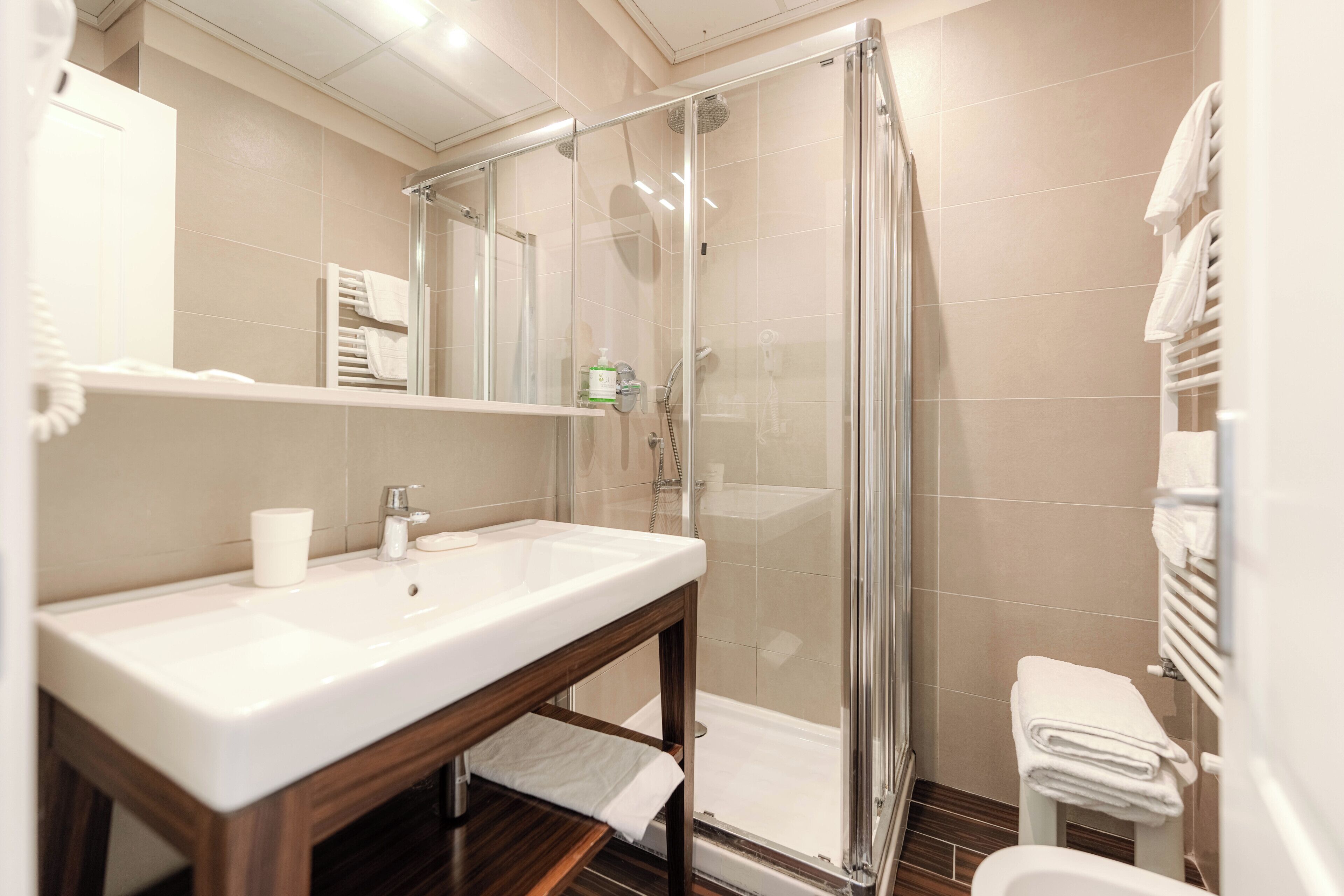 A bathroom with a glass-enclosed shower, a sink with a mirror, and a toilet.